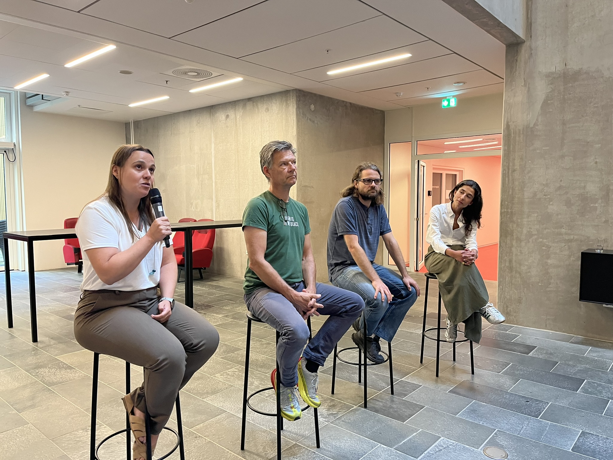 Four adults sit in a line on stools for a panel discussion