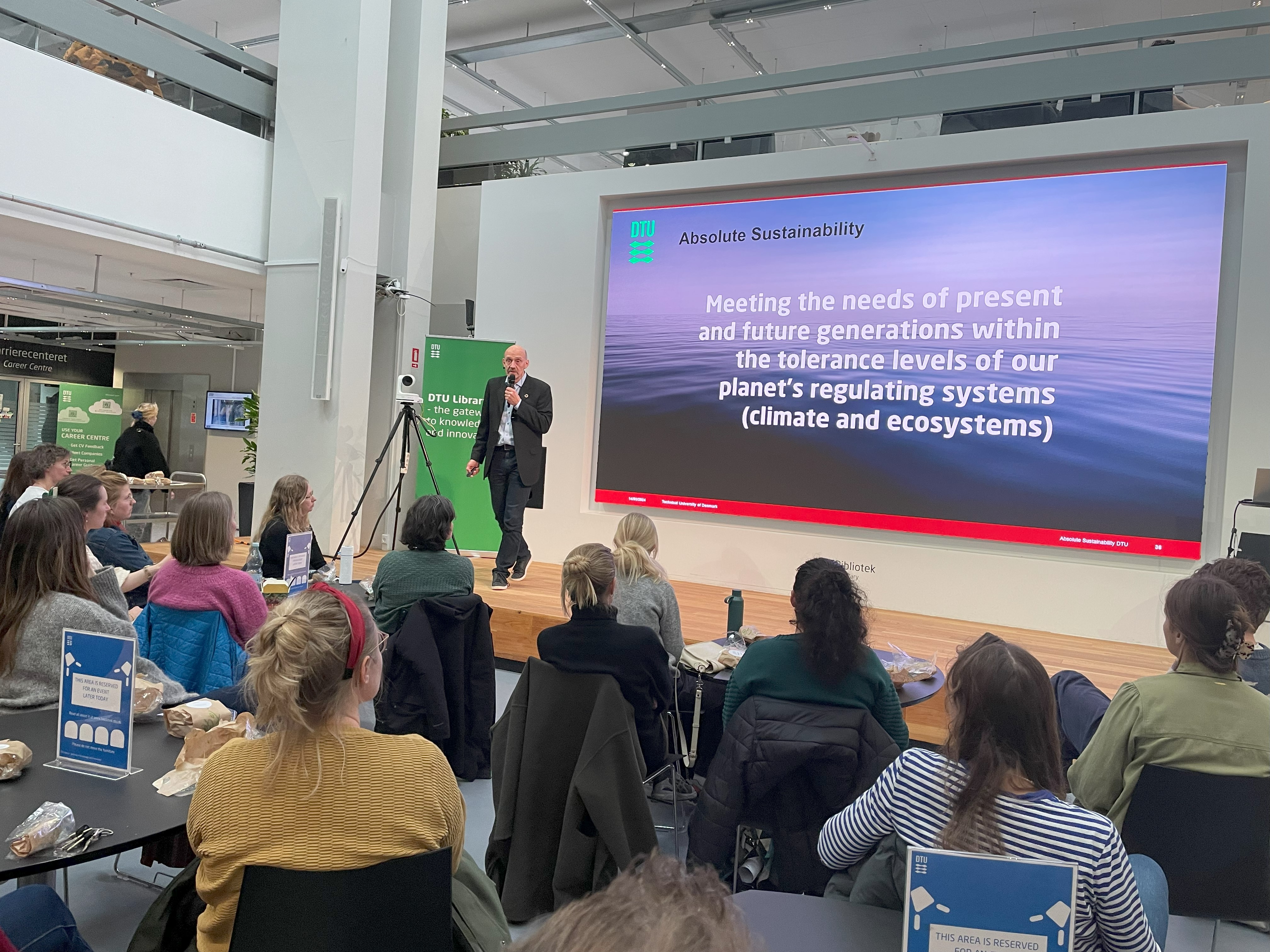Photo of a man presenting to a live audience 