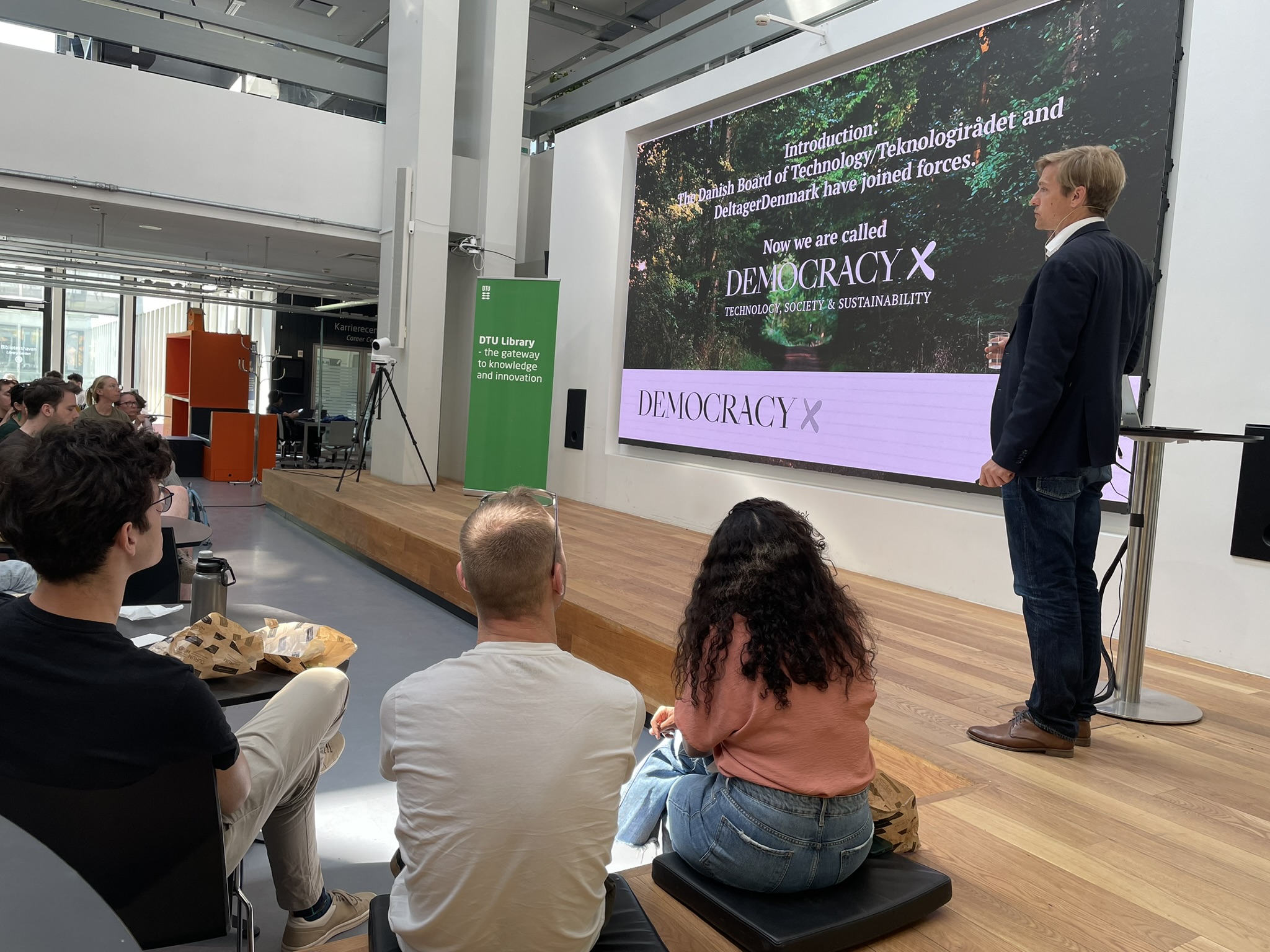 A photo of a crowd watching a man present in front of a screen